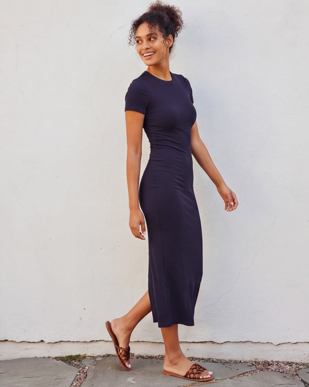 Woman wearing a fitted ribbed knit T-shirt midi dress with a crew neckline, short sleeves, body-skimming silhouette, and mid-calf length.