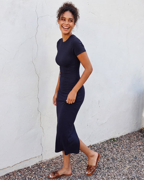 Woman wearing a fitted ribbed knit T-shirt midi dress with a crew neckline, short sleeves, body-skimming silhouette, and mid-calf length.