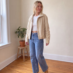 Woman wearing cream cropped cotton canvas jacket with white tee, high-waisted barrel jeans and tan kitten heels