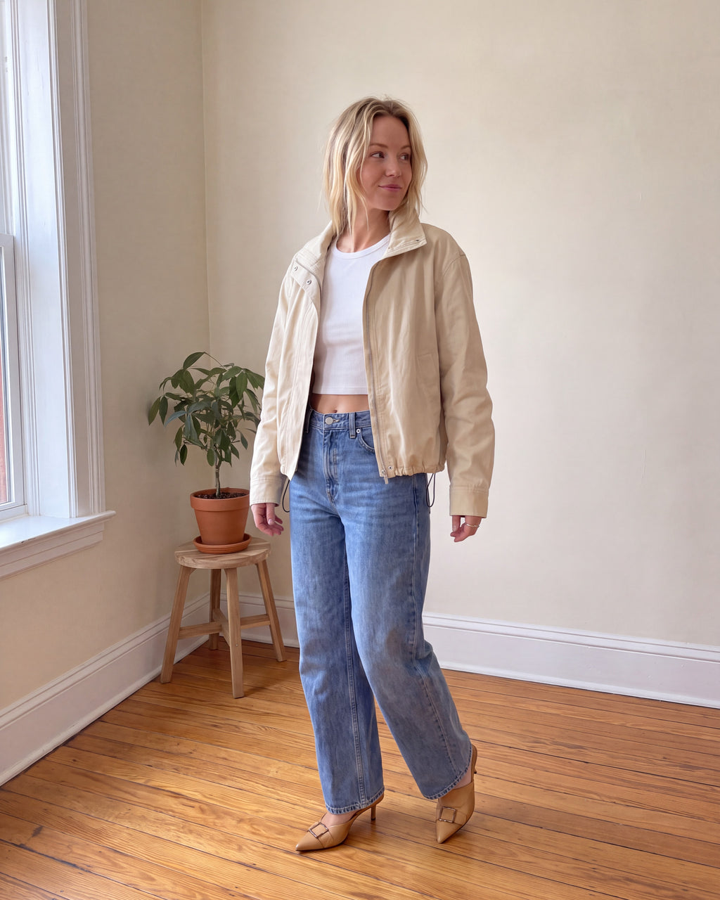 Woman wearing cream cropped cotton canvas jacket with white tee, high-waisted barrel jeans and tan kitten heels