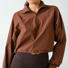 Women's chocolate brown half zip athleisure pullover with structured fit, long sleeves, four-way stretch fabric, and cropped silhouette.