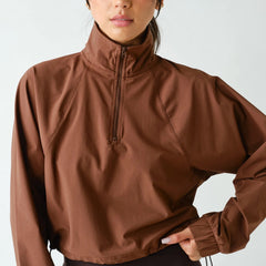 Women's chocolate brown half zip athleisure pullover with structured fit, long sleeves, four-way stretch fabric, and cropped silhouette.