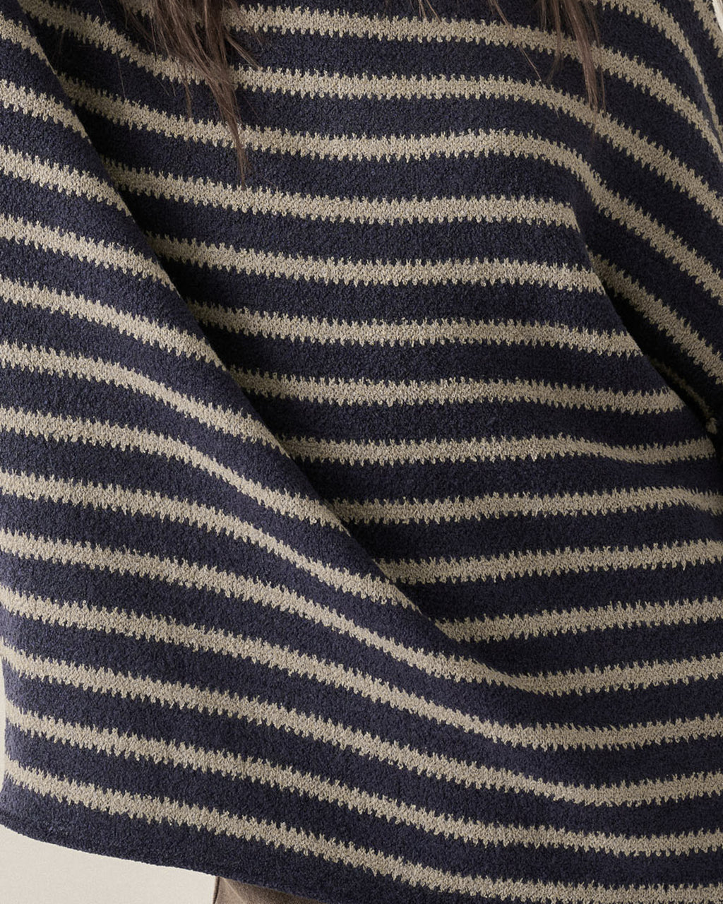 Close-up of a knit sweater with horizontal navy and gray stripes, showing the textured fabric and a small section of dark hair at the top.