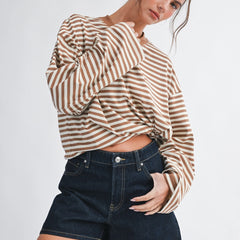 Woman wearing an oversized brown and cream striped long sleeve top with dropped shoulders styled with denim shorts.